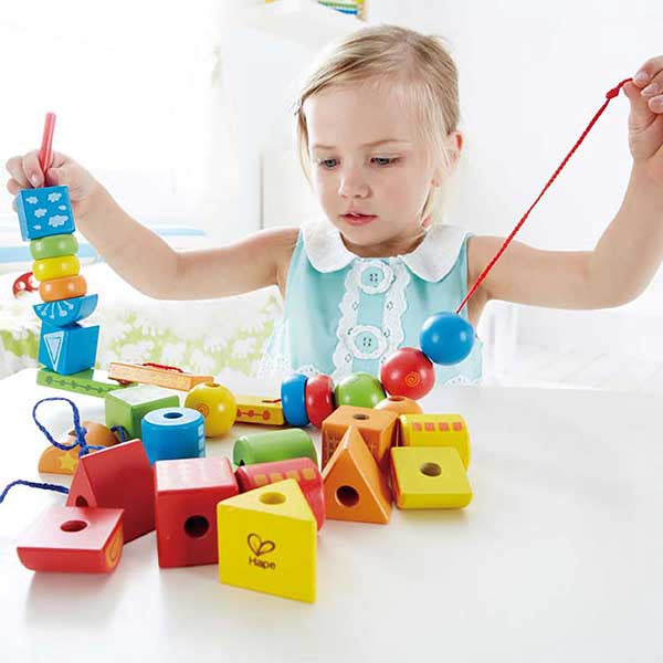 Child with lacing activity and wooden shapes